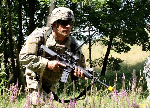 Staff Sgt. Oscar Morales, an infantryman and Arizona Army National Guardsman assigned to the 2nd Assault Helicopter Battalion, 285th Aviation Regiment, navigates through a field of high brush during the Multinational Battle Group-East's Best Warrior Competition held on Camp Bondsteel, Kosovo, July 9. (U.S. Army photo by: Staff Sgt. Thomas Duval, Multinational Battle Group-East Public Affairs)