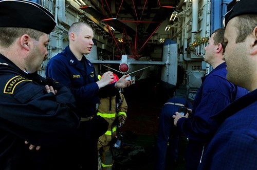 BALTIC SEA - Russian translator U.S. Navy Lt. Dmitry Shvets, second from left, narrates as Sailors assigned to the guided-missile cruiser USS Normandy (CG 60) demonstrate how to don firefighting equipment, while aboard Russian naval vessel Yaroslav Mudriy (727) during Exercise FRUKUS 2012. FRUKUS is an annual exercise aimed at improving maritime security through an open dialogue and increased training between the navies of France, Russia, United Kingdom and United States.