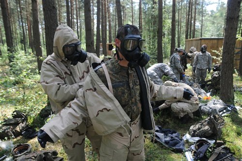 German 2nd Lt. Felix Honig, SanStff Mainz Hospital, assists German Sgt. Dustin Nicholas, 4th Company, 21st Hospital Regiment, with the removal of his chemical protective equipment during the demo phase of Combat Testing Lane 2 at the 2011 U.S. Army Europe Expert Field Medical Badge Standardization and Testing, August 2, 2011 at the Grafenwoehr Training Area, Germany.  CTL 2 tests candidates on their ability to perform basic Soldier skills while protecting themselves from a simulated Chemical, Biological, Radiological or Nuclear attack.  (U.S. Army photo by Army Staff Sgt. Thomas Wheeler)