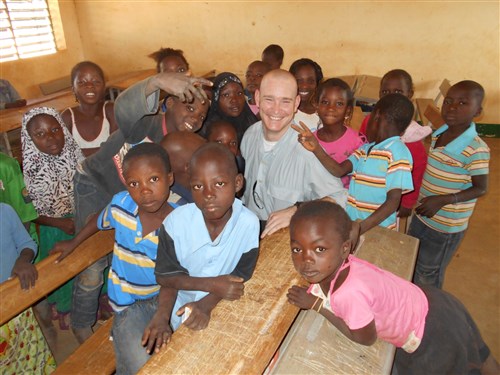 Military Intelligence Non-Commissioned Officer Course, 14-1, Ouagadougou, Burkina Faso, Officer In Charge, Captain Justin Moeykens poses with Burkinabe Elementary Students and Orphans during a community relations event on November 30th, 2013. (Photo by Courtesy Asset)