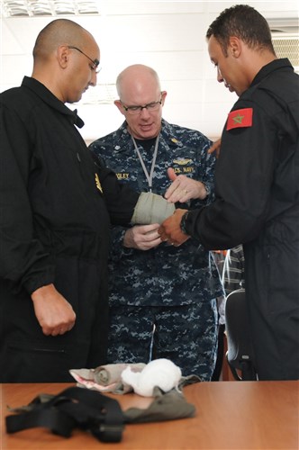 SOUDA BAY, Crete (May 25, 2011) -- U.S. Navy Cmdr.  John Quigley, exercise senior medical officer and Navy reserve component member from Sixth Fleet reserve detachment 802 in Atlanta, helps two Royal Moroccan military personal with the correct application of a tourniquet during exercise Phoenix Express 2011 (PE-11) on May 25, 2011. PE-11 is a multi-national maritime exercise comprising U.S., North African and European naval forces.  A three-week evolution divided into two phases of training, PE-11 is designed to enhance regional maritime partnerships among the 13 participating nations in their efforts to deter illicit trafficking at sea.  (U.S. Navy photo by Mass Communication Specialist 1st Class Edward Vasquez/Released)