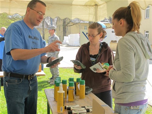 STUTTGART, Germany - Dr. (Colonel) John Andrus, U.S. Africa Command deputy command surgeon, explains the intricacies of treating your clothing with mosquito repellent to Nikka Brooks-Cullum and Violeta Hauser at AFRICOM's World Malaria Day tent on April 25, 2012.  (U.S. AFRICOM photo by Jan Childs)