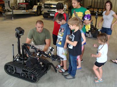 SSgt George Maize demonstrates the capability of a remote operated robot used in defusing unexploded ordnance at the EOD Compound on Aug. 31, 2016 for schoolchildren visiting the facility.