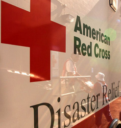 Side of Red Cross ERV with volunteers reflected in the side