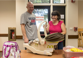 A father and his wife looking at their child on the table in a carrier.