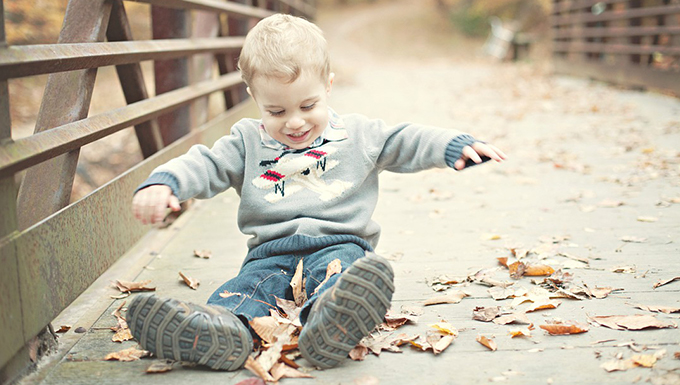 A child sitting on a pedestrian bridge playing.