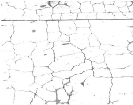 Photo shows a portion of the surface of a slab with a construction joint (or gap) separating two parts. Cracking has formed throughout the slab. The cracks are irregular in shape and pattern, except near the construction joint where they approach perpendicular to the joint.