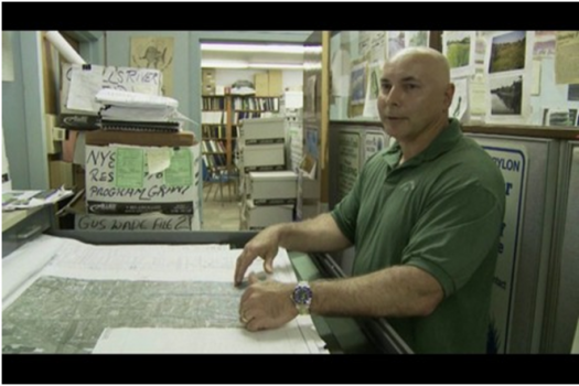 Video still from Risk MAP testimonial video of a man referencing a Flood Insurance Rate Map.