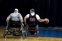 Chief Master Sgt. Lisa Arnold, 88th Air Base Wing command chief, gives chase to Mr. James Terpenning, an Air Force Life Cycle Management Center management analyst and member of the Miami Valley Raptors, during the 2nd annual wheelchair basketball game held as part of the National Disability Awareness Month activities, Oct. 26, at Wright-Patterson Air Force Base. Civilians and service members from around the base were able to play an exhibition game against four members from the Miami Valley Raptors and feel what it is like to play this popular sport while bound to a wheelchair. (U.S. Air Force photo/ Wesley Farnsworth)