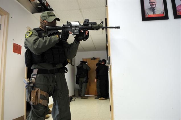 Agent Michael Rivera guards the hallway while investigators negotiate through the door with a woman who’s taken a bank hostage Dec. 13, 2013. This was one of four scenarios being acted out during the culmination of a week of crisis negotiation training that the FBI offered the Marine Corps Criminal Investigation Division. 