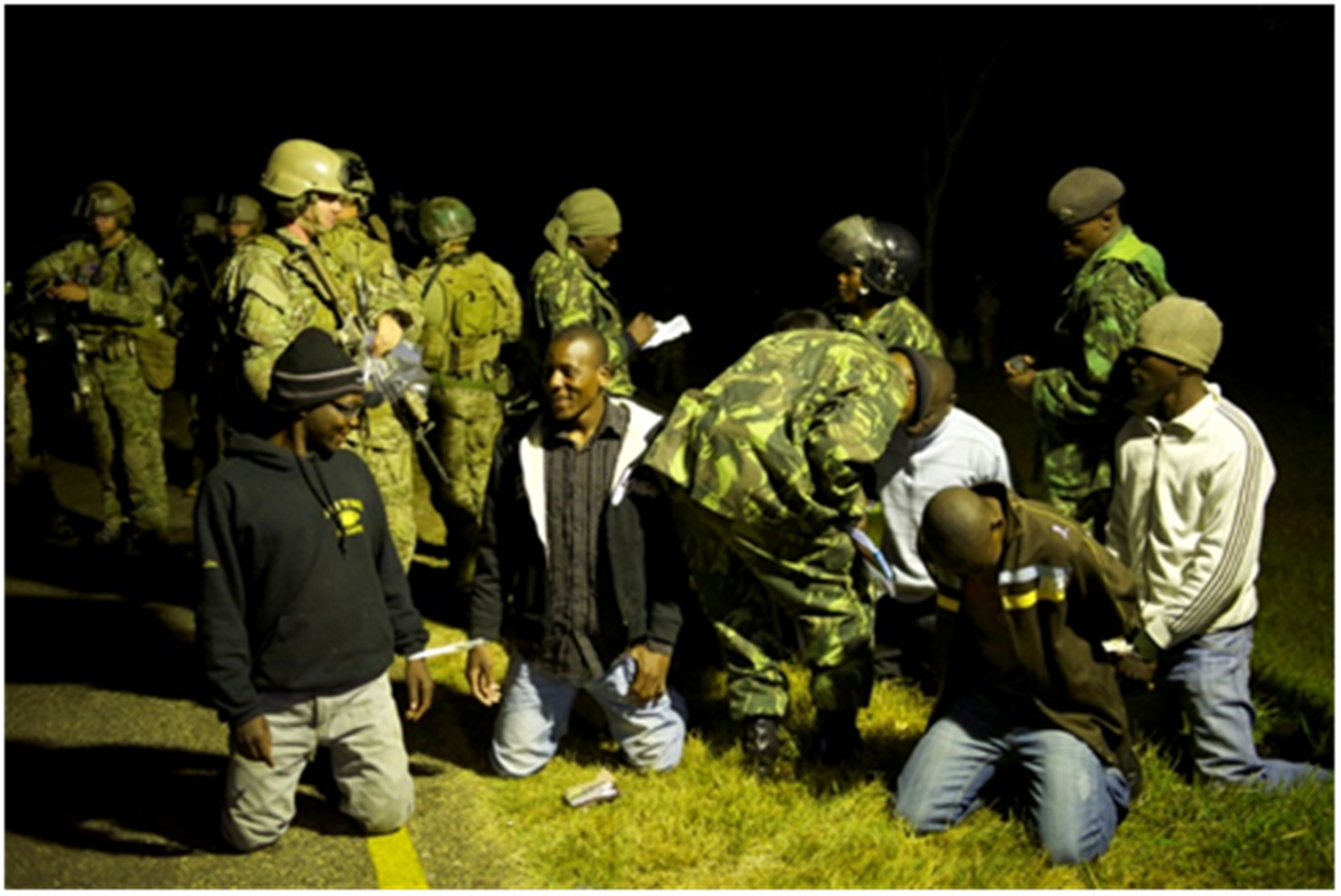 A U.S. Special Operations Forces troop watches as Malawi Defense Force Paratroopers search individuals following a simulated training scenario during Exercise Epic Guardian 2013.(U.S. Air Force photo by Master Sgt. Larry W. Carpenter Jr.)