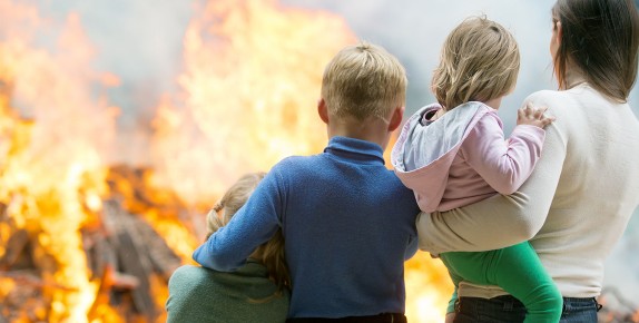 A sad family watches a large house fire.