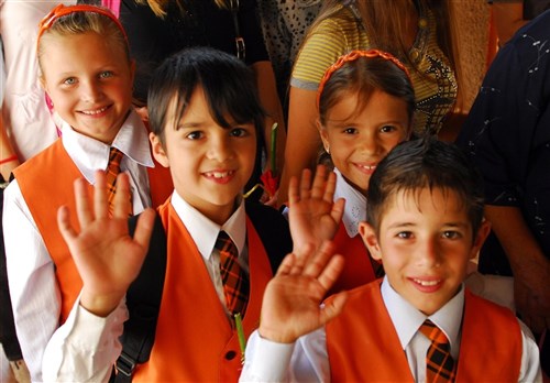 MIHAIL KOGALNICEANU, Romania &mdash; Students of Mihail Kogalniceanu Middle School wave as they begin their first day of school after a ribbon-cutting ceremony held to honor U.S. Navy Seabees, Sept. 14. U.S. Navy Seabees assigned to Naval Mobile Construction Battalion 11 in Gulfport, Miss., and U.S. Navy Seabees assigned to NMBC 3 in Port Hueneme, Calif., built a new perimeter fence in July and August as part of a Humanitarian Civil Assistance mission designed to strengthen relationships with local villages in Romania and Bulgaria as part of Joint Task Force-East. (Department of Defense photo by Army Pfc. Charles Thompson)