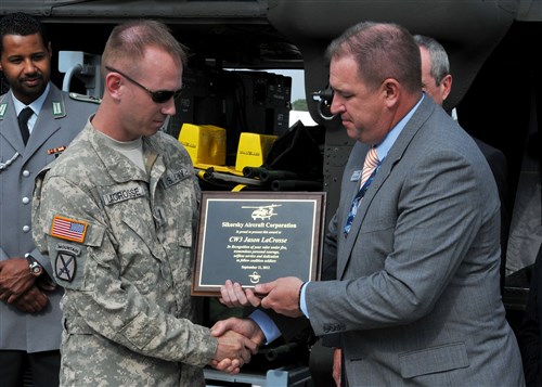 BERLIN - Army Chief Warrant Officer 3 Jason Lacrosse, UH-60 Black Hawk pilot, with the Joint Multinational Readiness Center Falcons, Hohenfels, Germany, is presented an award from the Sikorsky Aircraft Corporation by Robert Kokorda, Sikorsky Sales and Marketing vice president, at the Berlin Air Show here Sept. 11. Lacrosse received the award for heroic efforts that saved 12 German army soldiers April 2, 2010, in Afghanistan.