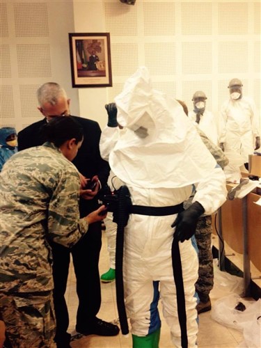 Infectious Disease Physician for the U. S. Defense Institute for Medical Operations (DIMO), Dr. Matthew Dolan, and Dr. Khadidja Harrell, International Health Specialist, Command Surgeon, help members of the Gabonese military with the proper steps of donning personal protective equipment (PPE) as part of a military-to-military engagement in Libreville, Gabon in October 2014.  DIMO, along with U.S. Africa Command and Gabonese Military Medical personnel and the country’s Ministry of Health (MOH) are in partnership for a mission to identify and develop the infection control activities framework that will strengthen Gabonese defense capabilities.  The partnership will also help to enhance the national and regional policies and security in the African country. (U.S. AFRICOM photo/Released).