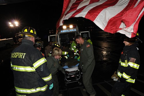 BOSTON, Massachusetts - An Air Force medical team from the 10th Expeditionary Aeromedical Evacuation flight passes a litter patient to a waiting team of firefighters at Logan International Airport in Boston, October 29, 2011. The patient is one of 22 Libyan freedom fighters who flew from Tripoli to Boston. The Libyan freedom fighters will receive specialized surgical treatment at Boston's Spaulding Rehabilitation Center. (Photo by Rich Bartell, U.S. Army Africa Public Affairs Office)