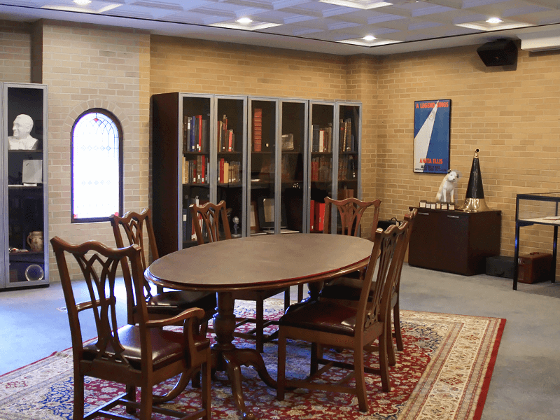 table with chairs, piano, glass cases, and picture hanging on the wall 