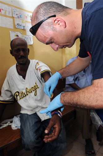 DJIBOUTI, Africa (April 30, 2011) - U.S. Navy Petty Officer 1st Class Joseph Sousa, Combined Joint Task Force - Horn of Africa surgical technician, uses medicated gauze to clean a wound on the forearm of a Djiboutian man April 30 at the Roman Catholic Diocese of Djibouti. Sutures on the man's hand were also examined. (U.S. Air Force photo by Staff Sgt. R.J. Biermann)