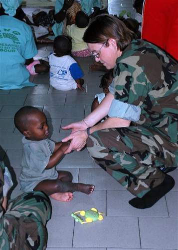 DAKAR, Senegal - Captain Cynthia Thebaud, commander of Africa Partnership Station (APS), plays with a child at the Vivre Ensemble orphanage in Dakar, Senegal after a team of APS Nashville crew members delivered donated school supplies from Project Handclasp, February 7, 2009. The Norfolk-based amphibious transport dock ship, USS Nashville (LPD 13), is deployed as a part of Africa Partnership Station, an international initiative developed by U.S. Naval Forces Europe and Naval Forces Africa, which aims to work cooperatively with U.S. and international partners to improve maritime safety and security in Africa. (U.S. Navy photo by Petty Officer 2nd Class David Holmes)