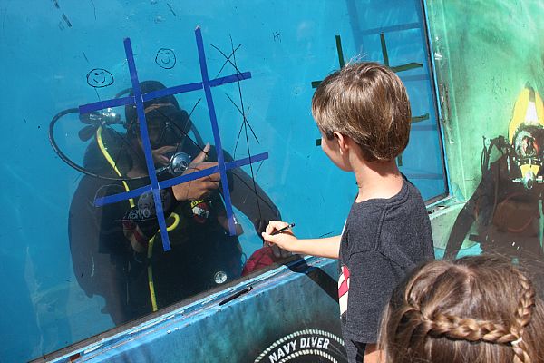 PHOENIX (March 30, 2012) Hospital Corpsman 3rd Class Nathan Largent, assigned to Explosive Ordinance Disposal Mobile Unit (EOD MDSU) 1, based in San Diego, plays Tic-Tac-Toe with a child during Phoenix Navy Week, one of 15 Navy Weeks planned across America this year. Navy Weeks are designed to increase awareness in cities that do not have a significant Navy presence. U.S. Navy photo by Chief Mass Communication Specialist Steve Carlson.