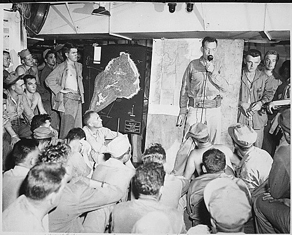U.S. Marines participate in an Iwo Jima pre-invasion briefing, February 1945. The 8-square-mile island, about halfway between mainland Japan and U.S. bases in the Mariana Islands, was considered strategically important as an air base for fighter escorts supporting bombing missions against Japan. DoD photo