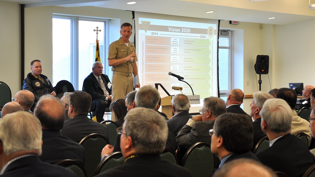 NAVAL AIR SYSTEMS COMMAND, PATUXENT RIVER, Md. -- Rear Adm. Paul Sohl (standing), Commander, Fleet Readiness Centers (COMFRC), Brig. Gen. Greg Masiello (left, seated), assistant commander for Logistics and Industrial Operations (AIR 6.0); and Dennis West (center, seated), deputy commander COMFRC, stressed the need for strategic partnerships with industry and across the Naval Aviation Enterprise (NAE) to fulfill Vice Adm. Grosklags’ imperatives of readiness, speed to fleet and affordability. The leaders presented “Key Enablers to Fleet Readiness” at a Patuxent Partnership program Feb. 2 at the Southern Maryland Higher Education Center, California, Maryland. U.S. Navy photo 