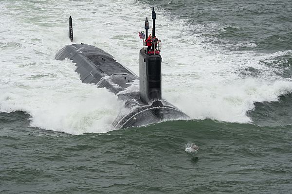 ATLANTIC OCEAN (May 21, 2015) A dolphin jumps in front of the Virginia-class attack submarine Pre-Commissioning Unit (PCU) John Warner (SSN 785) as the boat conducts sea trials in the Atlantic Ocean. U.S. Navy photo courtesy of Huntington Ingalls Industries by Chris Oxley.