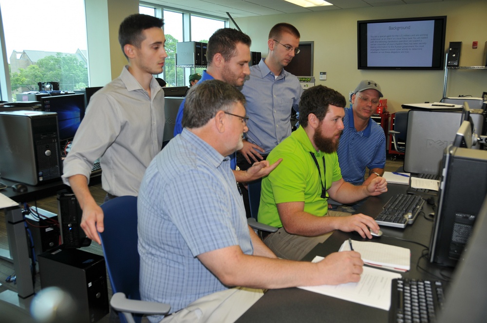Naval Research Enterprise Internship Program (NREIP) interns describe the Capture the Flag (CTF) cybersecurity challenge to Naval Surface Warfare Center Panama City Division (NSWC PCD) employees during the CTF event at Gulf Coast State College on July 15, 2016. Pictured from left to right: NREIP intern Trevor Phillips, Mark Bates, NREIP intern Daniel Jermyn, Josh Westmoreland, David Cole and Tim McCabe. U.S. Navy Photo by Katherine Mapp