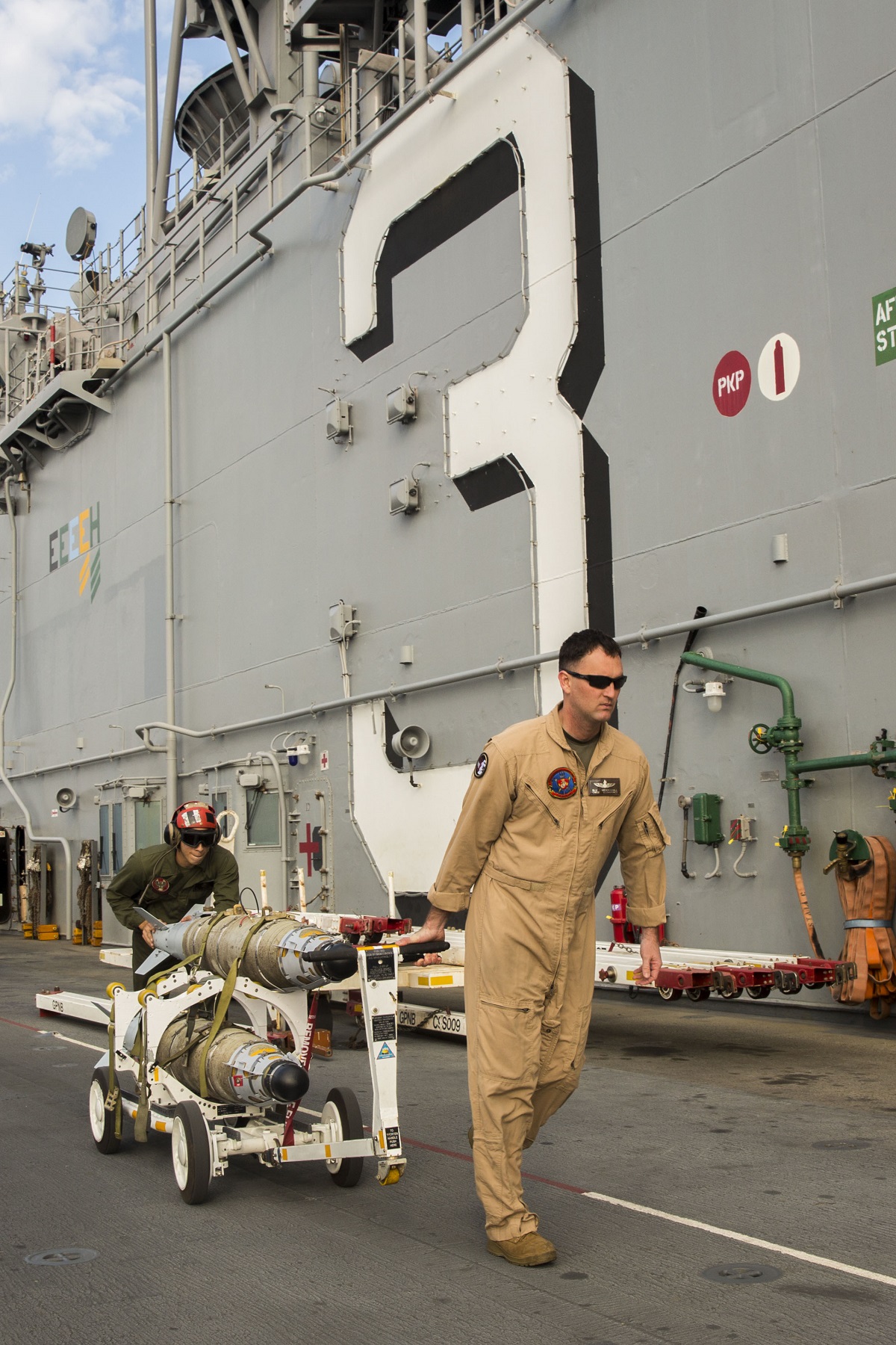 ARABIAN GULF (Dec. 4, 2015) Cpl. Douglass Valle (left), from Miami, and Chief Warrant Officer 2 Nickolas "Blu" Mendenhall, from Smithville, Texas, both assigned to the Air Combat Element (ACE) of the embarked 26th Marine Expeditionary Unit (MEU), transport ordnance on the flight deck of the amphibious assault ship USS Kearsarge (LHD 3). Kearsarge is deployed to the U.S. 5th Fleet, supporting Operation Inherent Resolve, the effort to degrade and ultimately destroy ISIL; maritime security operations, and regional theater security cooperation efforts.  U.S. Navy photo by Mass Communication Specialist Seaman Apprentice Ryre Arciaga
