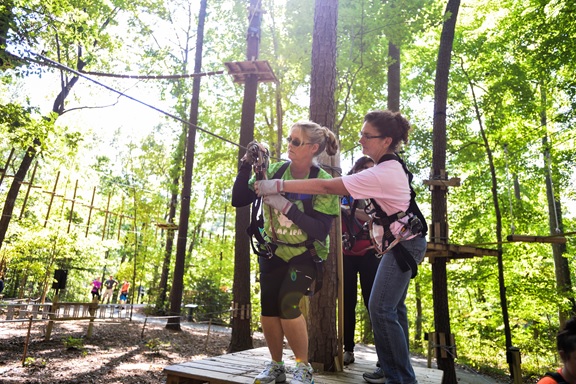 VIRGINIA BEACH, Va. (October 08, 2015) — Participants of the Navy Information Dominance Forces Senior Leadership Development Program (SLDP) assist one-another as they prepare to “zip” across a zip line during a one-day skill-building event at The Adventure Park at Virginia Aquarium, Virginia Beach, Va.  The one-day skill-building event is part of a 10-month course based on the Office of Personnel Management's (OPM) five Executive Core Qualifications: Leading Change, Leading People, Results Driven, Business Acumen and Building Coalitions.  U.S. Navy photo by Michael J. Morris  