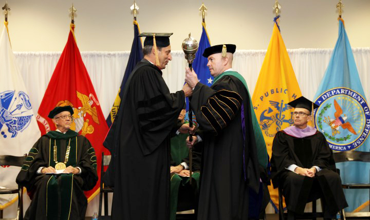 The Honorable Peter Levine, performing the duties of the under secretary of Defense for Personnel and Readiness, presents the ceremonial mace to Dr. Richard W. Thomas, president of the Uniformed Services University of the Health Sciences, officially installing Thomas as the university's sixth leader (Photo by Air Force SSgt. Stephanie Morris, Uniformed Services University).