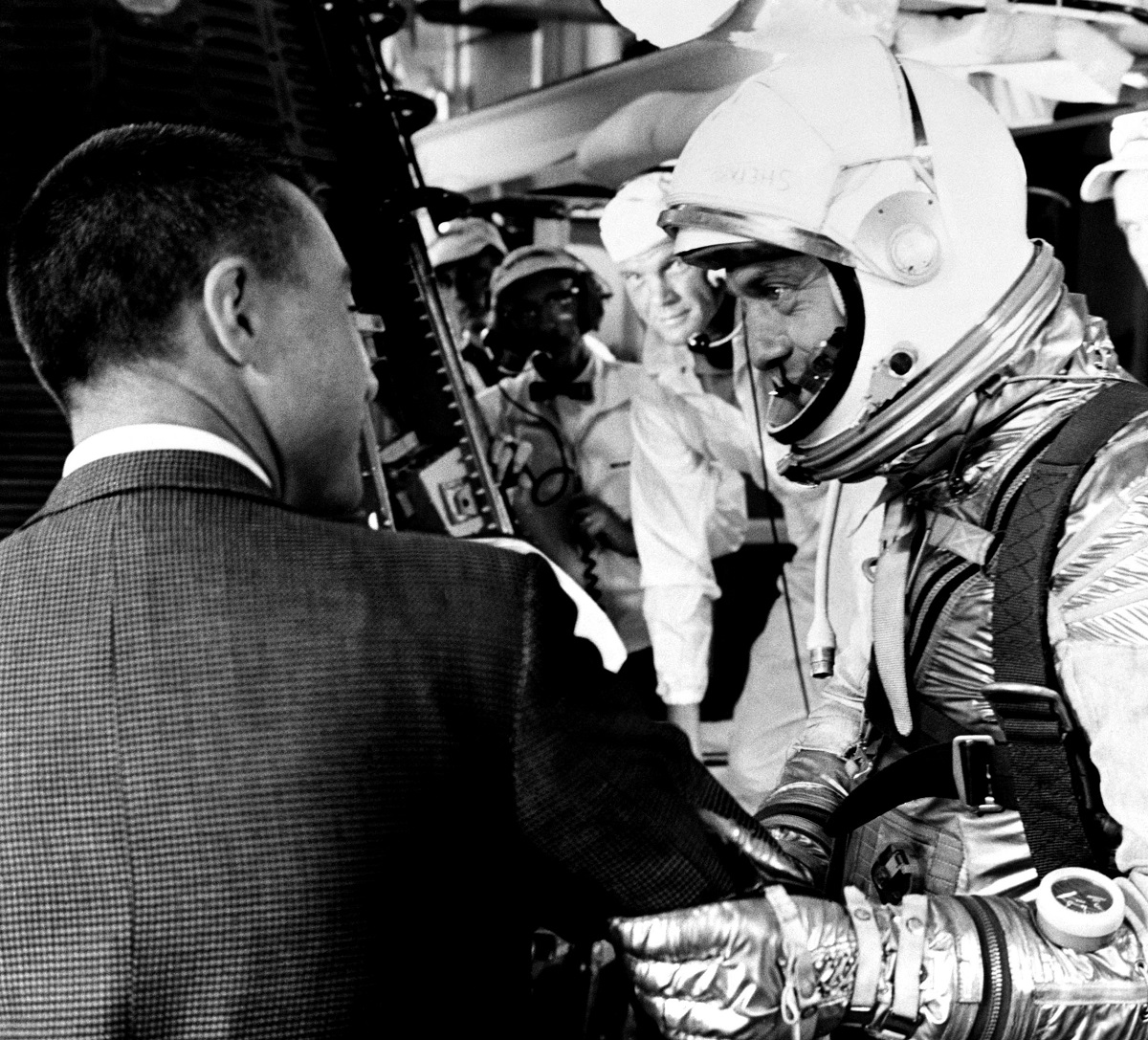 Alan Shepard speaks with Gus Grissom (on left, back to camera), prior to climbing aboard his Freedom 7 capsule for his Mercury-Redstone 3 mission on May 5, 1961. John Glenn (behind Shepard) waits to help strap Shepard into the spacecraft. Image Credit: NASA.