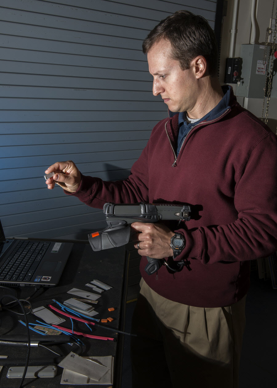 Dustin Barnes, a research analyst with Innovative Professional Solutions, Inc., shows off one of several types Radio Frequency Identification Devices (RFID) tags used by the Naval Surface Warfare Center Panama City Division (NSWC PCD) team. This particular RFID tag is commonly referred to as a chiclet and was selected for its compatibility with metal. Photo by Ron Newsome, NSWC PCD.

