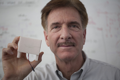 Professor David Jenn with the NPS Department of Electrical and Computer Engineering holds his recently patented Dipole with an Unbalanced Microstrip Feed antenna. The tiny antenna, known in the industry as a “rectenna,” captures ambient electromagnetic waves and converts them to usable current. Photo courtesy of NPS.