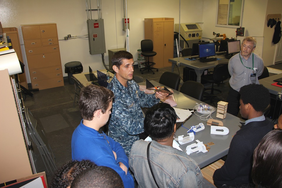 Mid-Atlantic Regional Maintenance Center Fab Lab officer Lt. Todd Coursey shows a completed project from the Fab Lab to students from Heritage High School’s Governor’s STEM program. U.S. Navy photo by Aaron Strickland, Public Affairs Specialist