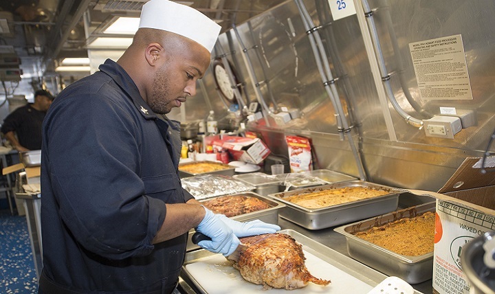 Navy Petty Officer 1st Class Jonathan Lewis carves turkey for a holiday dinner aboard USS Coronado.