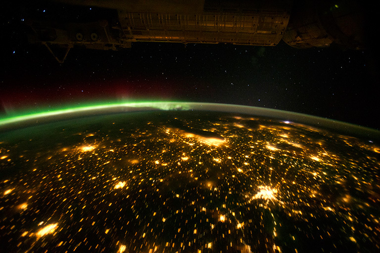 The Midwestern United States illuminated by a patchwork quilt of light as seen from the International Space Station (ISS). The aurora borealis also shines brightly in this view.