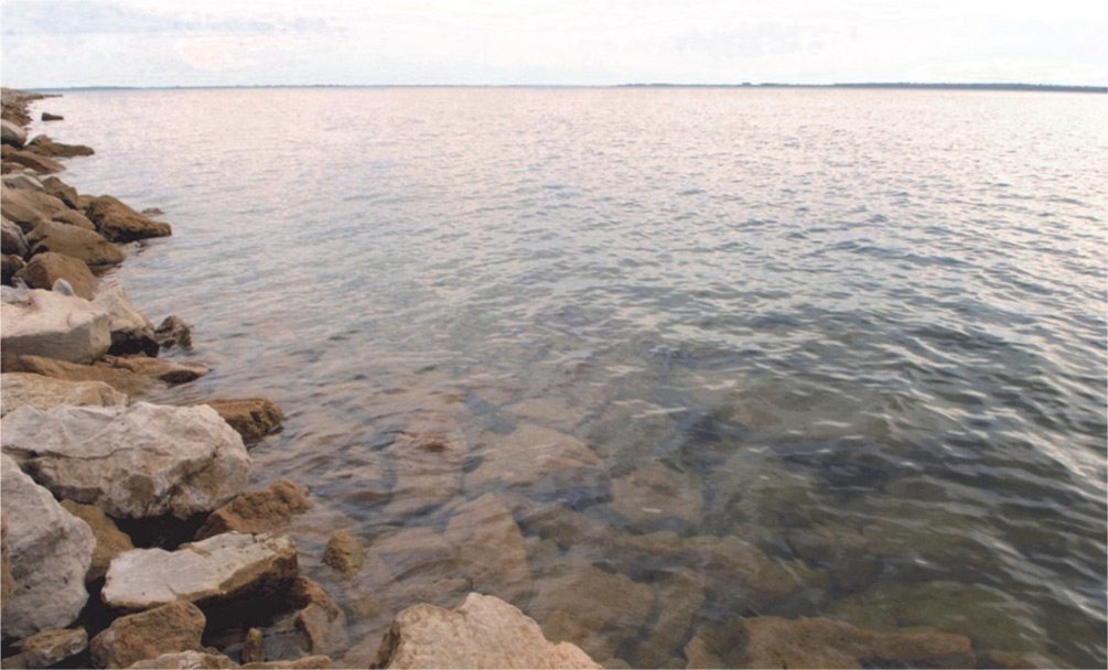 Lake Sakakawea with blue sky in the background and rocks on the left side of the photo.
