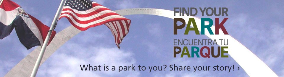 Flags flying near Gateway Arch with Find Your Park and Encuentra Tu Parque logos