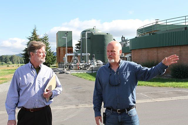 Alan Johnston from the City of Gresham Wastewater Services Division gives a tour of the energy positive Gresham Wastewater Treatment Plant in Oregon. In the background is the receiving station for fats, oils, and grease from local food establishments that increase biogas production for conversion to electricity Photo credit: Jim Swenson, New Media Magic LLC 
