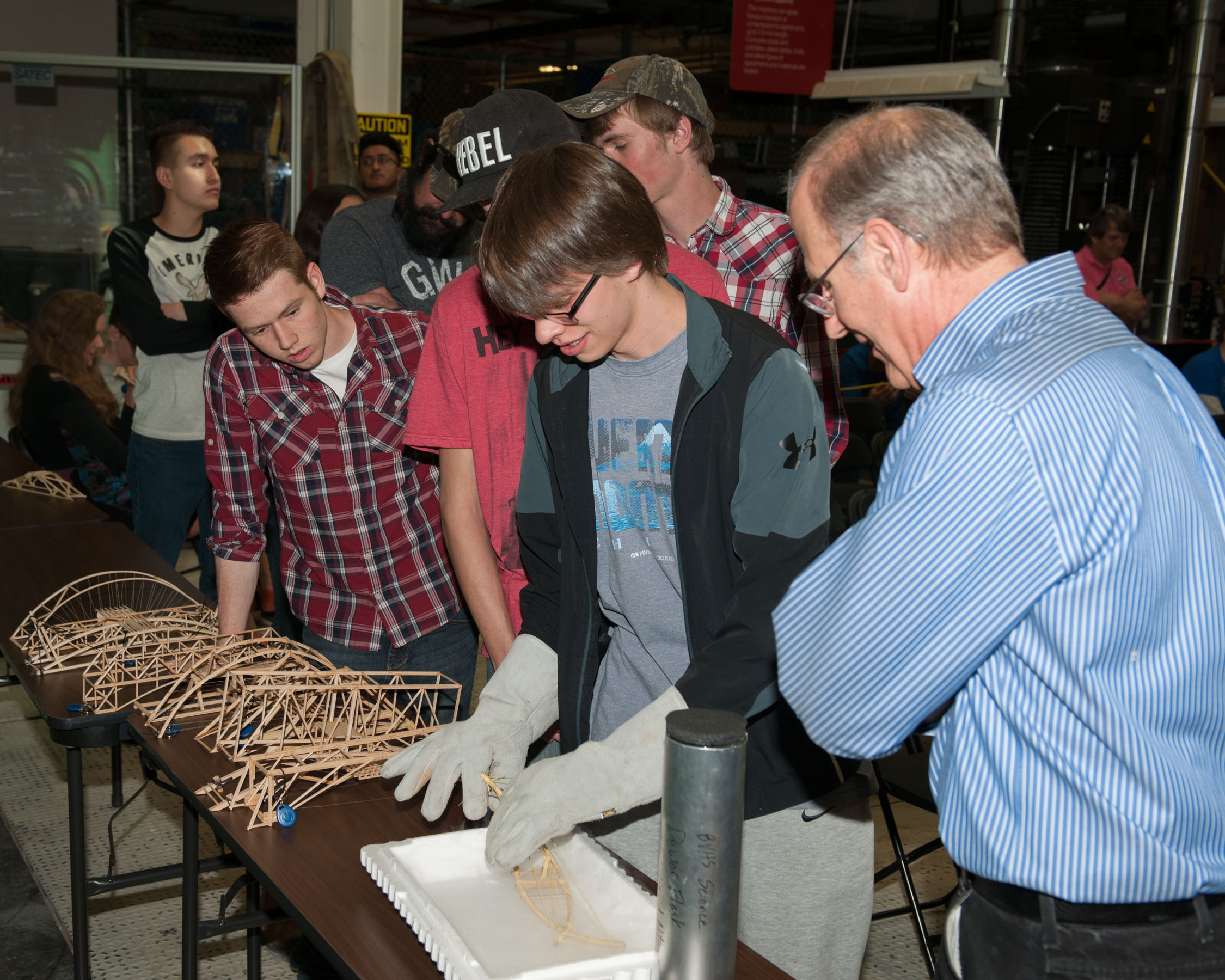 Students test their bridges with the help of volunteers