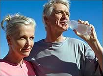 Older adult couple drinking water outside.
