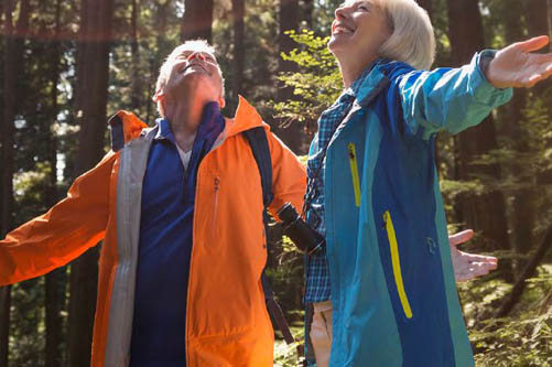 Two older adults looking to the sky in a forrest