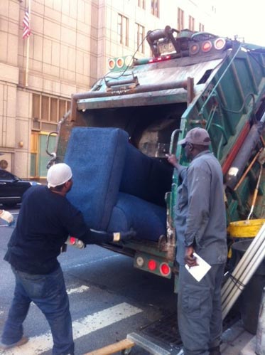 Sanitation workers crush a curbside couch.