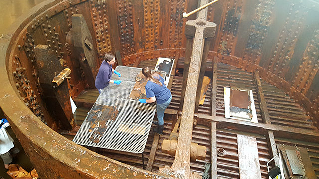 Conservators place the nut guards that were removed onto the anode table