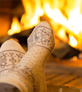 feet wearing cozy socks propped up near a fireplace