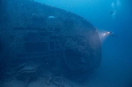 em clark on it's side with divers examining the wreck