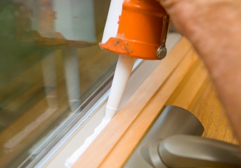 Applying caulk to a window frame to prevent air leakage. This caulk is white when applied, and dries clear. | Photo courtesy of Â©iStockphoto.com/BanksPhotos.