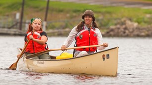 Two paddlers float down the river in their canoe.