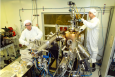 Inside a clean room, Brookhaven physicists Ivan Bozovic (left) and Anthony Bollinger work on the molecular beam epitaxy system that produced the atomically perfect materials used in the study. | Photo courtesy of Brookhaven National Lab